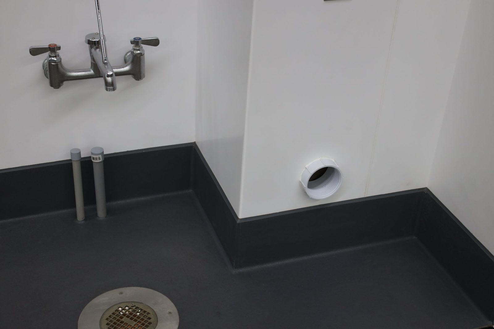 Eco-Grip flooring welded tight to a floor drain and floor sink in a commercial kitchen
